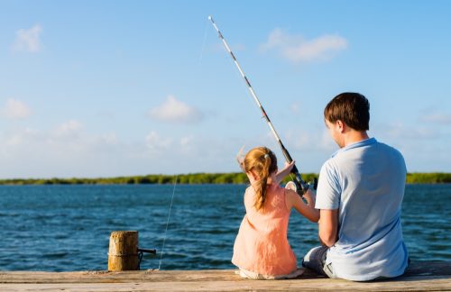 father and daughter sitting on a pier fishing