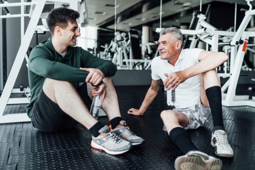 father and son sitting on the floor at the gym