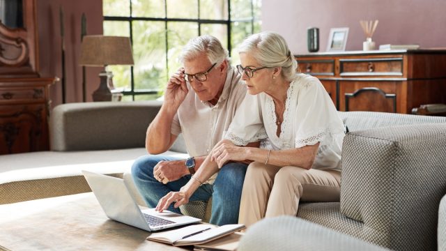 Shot of a mature couple using a laptop while calculating their finances together at home
