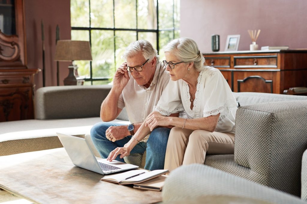 older couple looking at a computer screen together with documents next to them