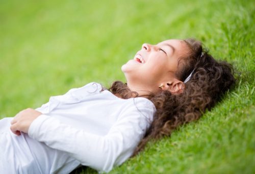 little girl laying in the grass laughing at funny jokes