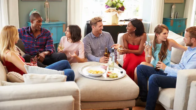 Group Of Friends Relaxing At Home In Living Room With Drinks Together