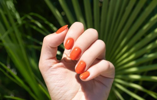 Female hand with orange nail polish