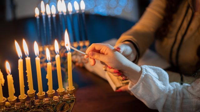 family lighting menorah candles during Hanukkah