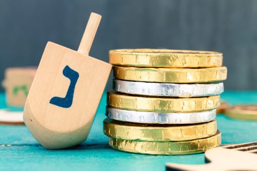Close up of Hanukkah gelt or money or coins with Hanukkah dreidel.