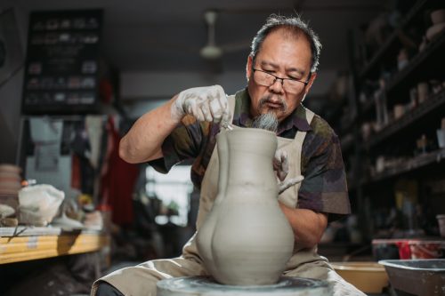 older man making pottery