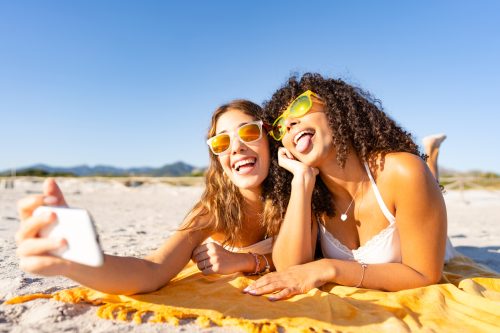 hai người phụ nữ nói chuyện selfie trên bãi biển