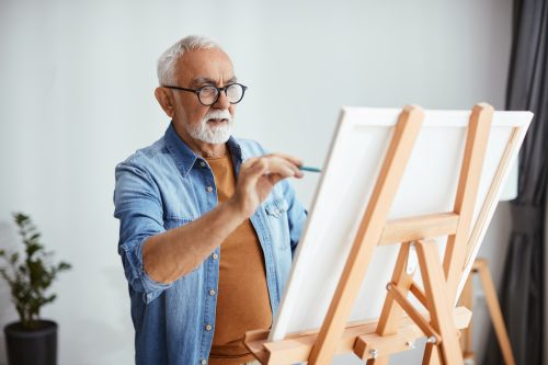 older man painting on canvas