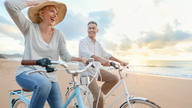 older couples riding bikes on the beach