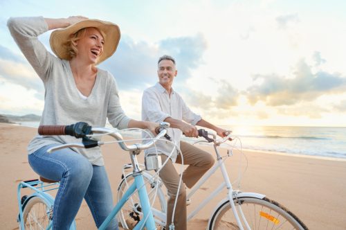 older couples riding bikes on the beach