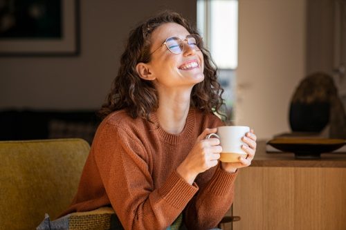 woman smiling while drinking her morning coffee