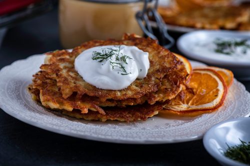 Potato pancakes or latke served with sour cream, dill, and applesauce.