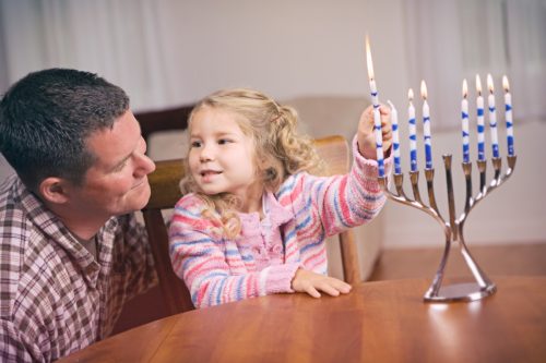 Man And Daughter Light Hanukkah Candles