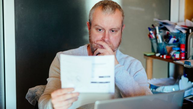 A man looking at a bill or piece of tax information with a worried expression
