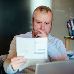A man looking at a bill or piece of tax information with a worried expression