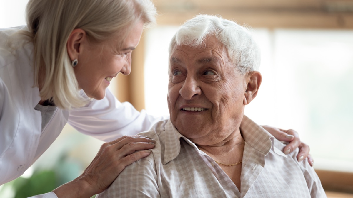 Close up middle-aged woman supporting older dementia patient, touching his shoulders, giving psychological help