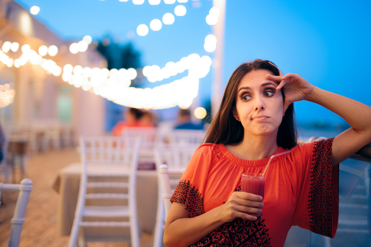 Bored girl at an outdoor restaurant having a drink waiting for her boyfriend