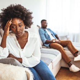Unhappy Couple After an Argument in the Living Room at Home. Sad Pensive Young Girl Thinking of Relationships Problems Sitting on Sofa With Offended Boyfriend, Conflicts in Marriage,