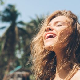 woman smiling in the sunshine while repeating positive affirmations