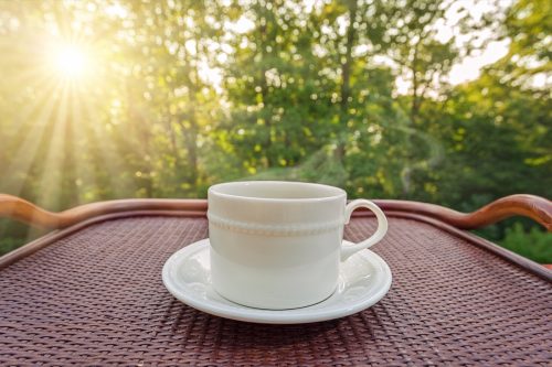 a cup of coffee on an outdoor table in the morning