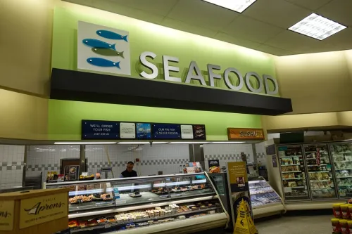 The seafood department in a grocery store with an employee behind the counter.