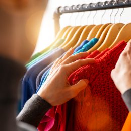 Fashion clothes hanging on clothing rack, in colorful rainbow colors