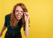 Redheaded woman with glasses looking at the camera with surprise