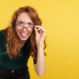 Redheaded woman with glasses looking at the camera with surprise