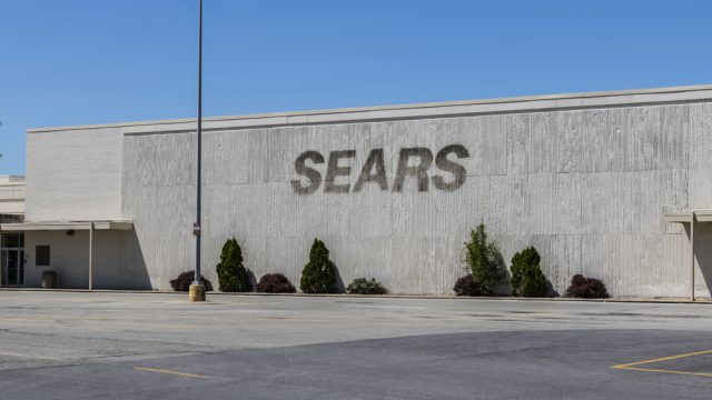 A storefront of a closed Sears location with the sign removed