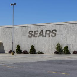 A storefront of a closed Sears location with the sign removed