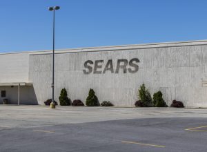 A storefront of a closed Sears location with the sign removed