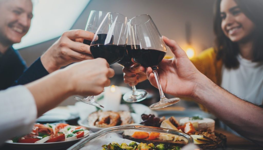Group of friends toasting with red wine over dinner