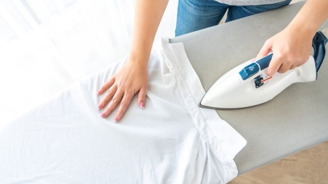 woman ironing shirt on ironing board