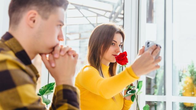 young woman taking selfie while partner watches