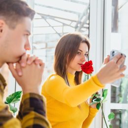 young woman taking selfie while partner watches