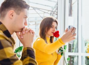 young woman taking selfie while partner watches