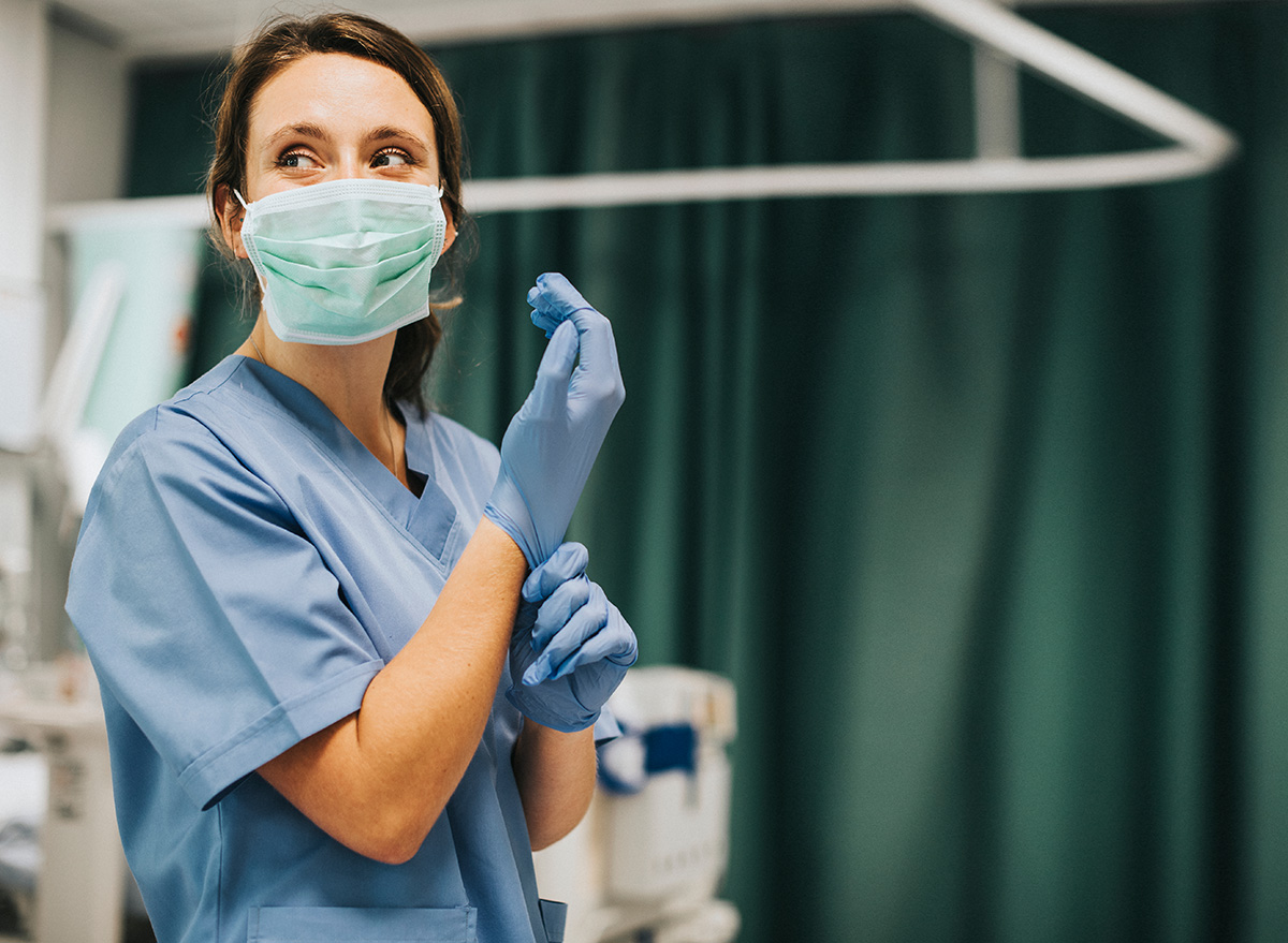 Nurse with mask on wearing blue scrubs and gloves