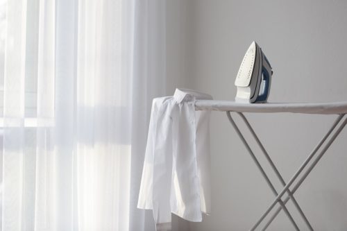 iron and shirt on ironing board
