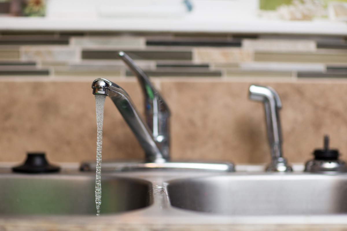 Shallow depth of field view of a kitchen sink with the water running