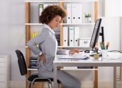 Doanh nhân trẻ bị đau lưng khi làm việc tại văn phòng
