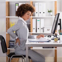 Young Businesswoman Suffering From Back Pain While Working In Office