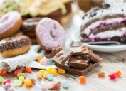 đồ ăn nhẹ, đồ ngọt và khái niệm ăn uống không lành mạnh - cận cảnh những miếng sô cô la, đậu thạch, bánh rán tráng men và bánh ngọt trên bàn gỗ