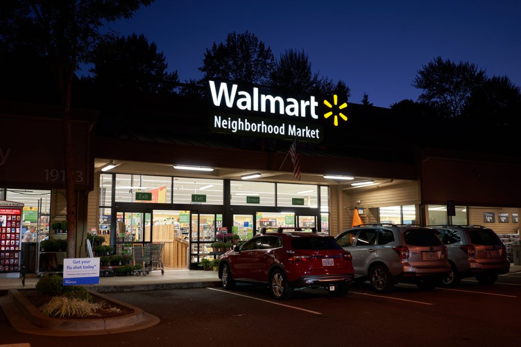 The exterior of a Walmart Neighborhood Market at night with its sign illuminated