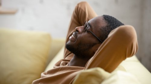 man relaxing while repeating positive affirmations on the couch