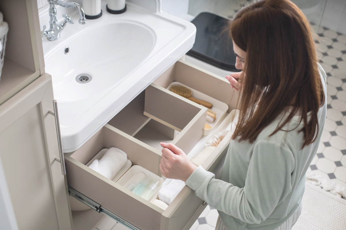Top view of a woman organizing the drawer underneath the sink in her bathroom