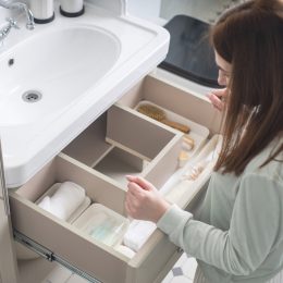 Top view of a woman organizing the drawer underneath the sink in her bathroom