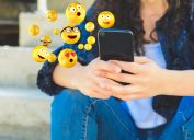 Close-up of woman using smartphone sending emojis.