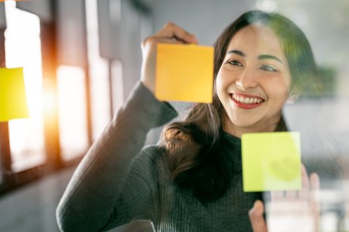young woman writing on post-it notes