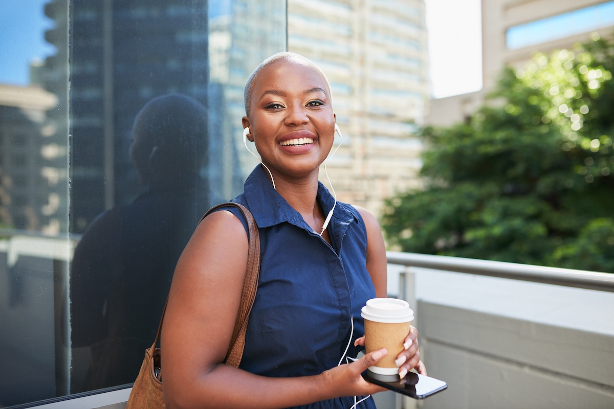 A young businesswoman arrives at the office with coffee and smile