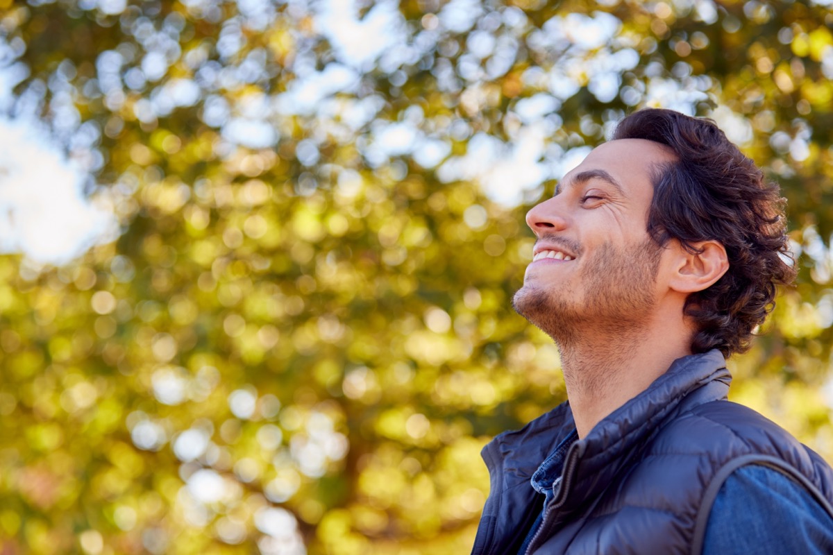 Calm Man Outside Smiling with his eyes closed among trees